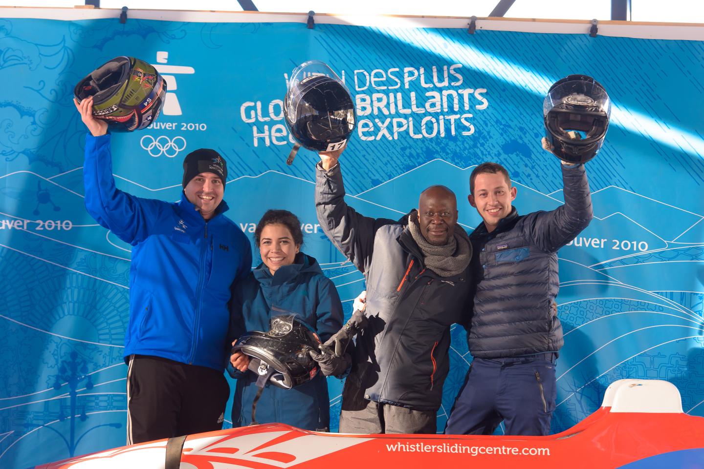 people holding up helmets celebrating their bobsled ride