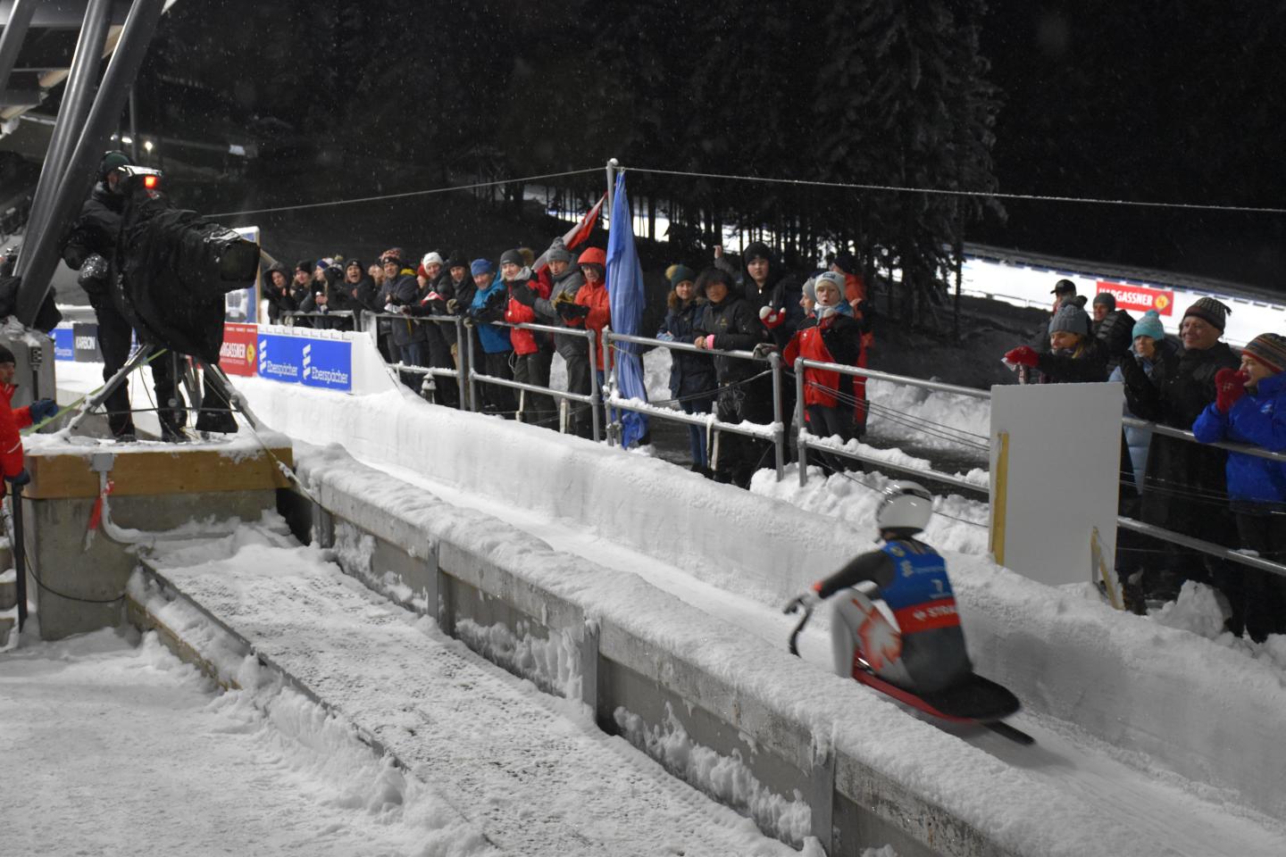 luge athlete on track with spectators