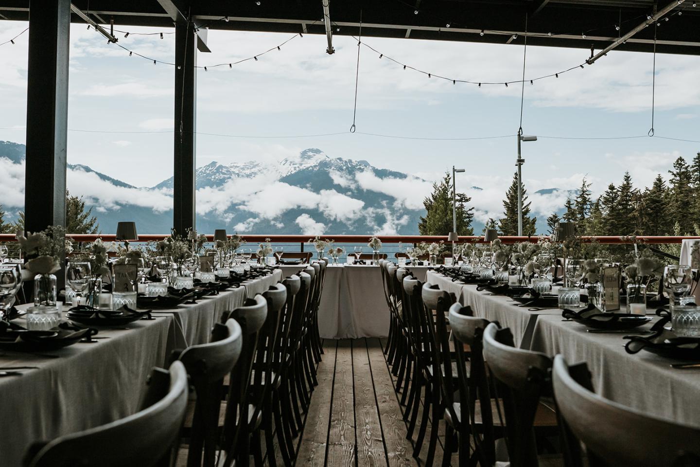 Outdoor dining setup with mountain view and string lights.