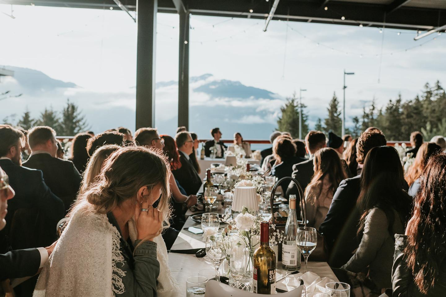 Guests seated at an outdoor wedding reception under a canopy with mountain views.