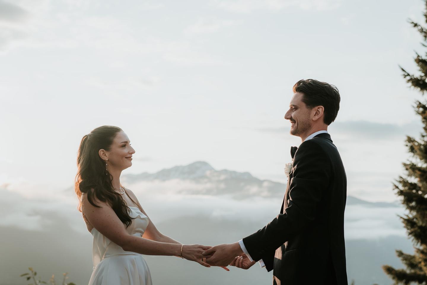 Bride and groom holding hands, mountains in the background.
