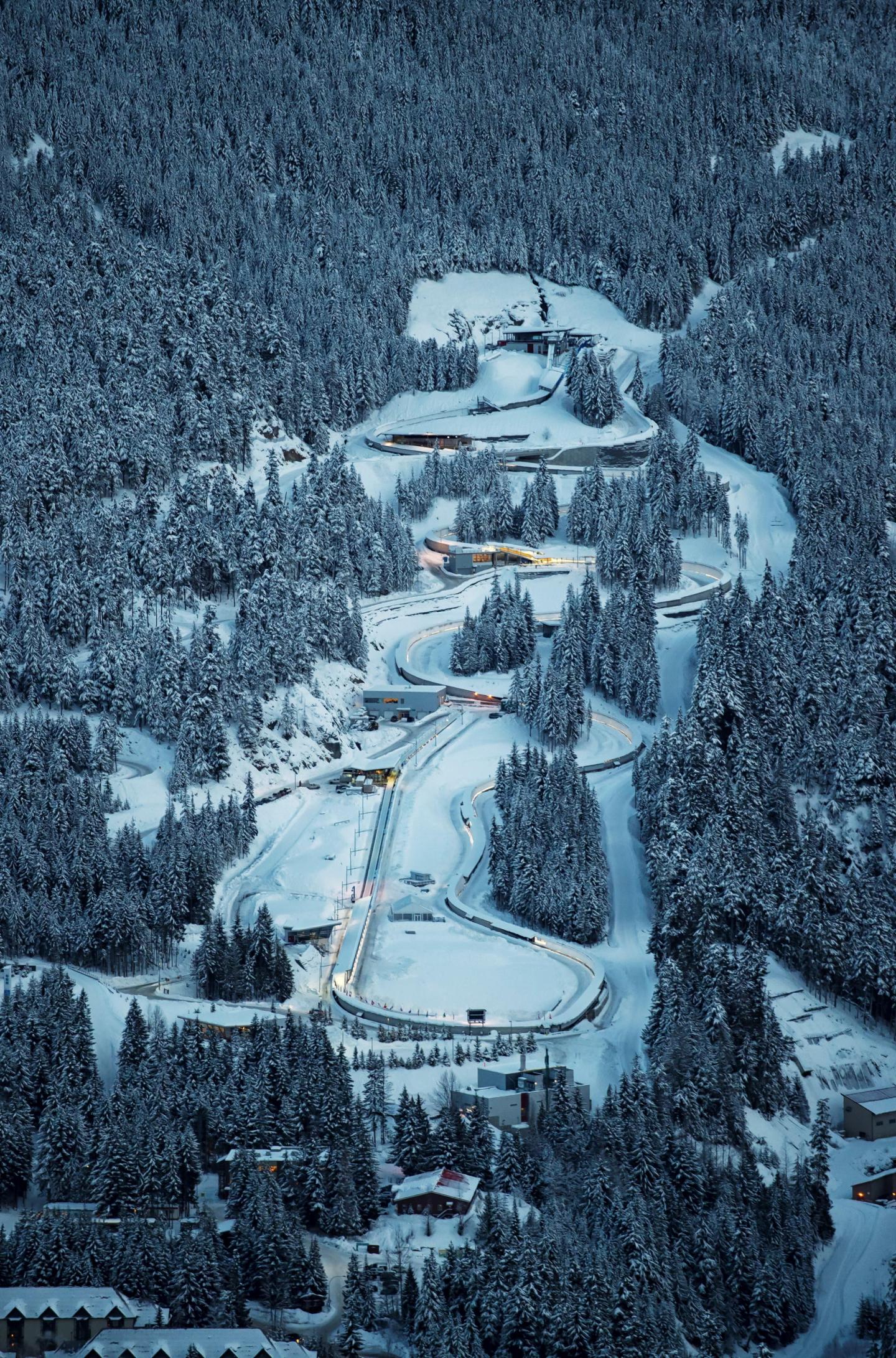 Snowy forest with winding road at dusk.