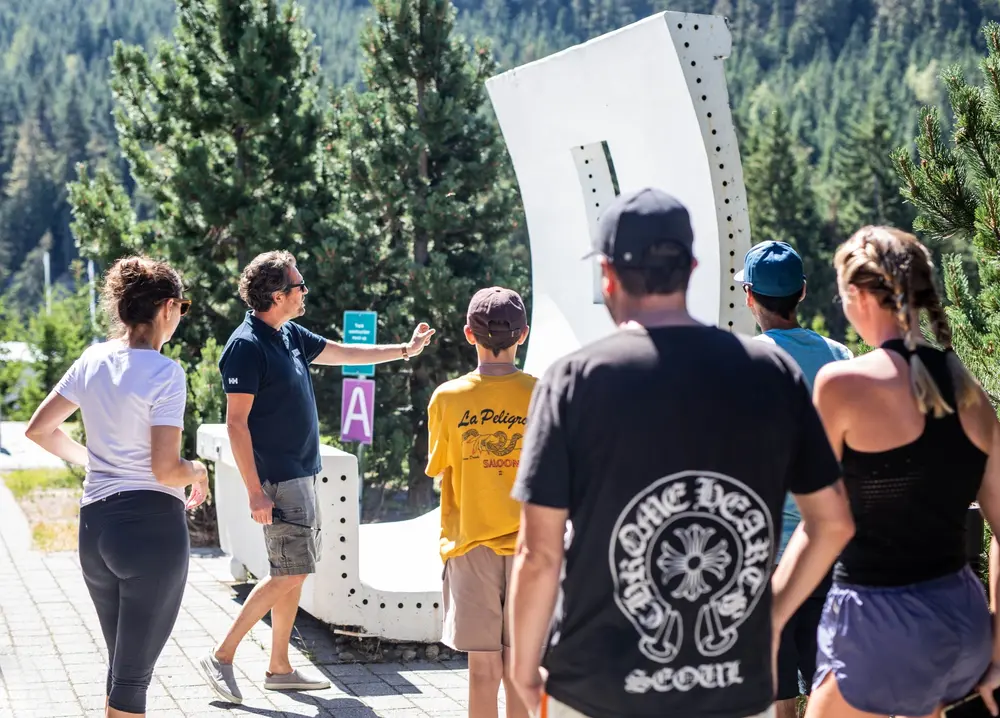Group of people exploring an outdoor art installation in a forested area.