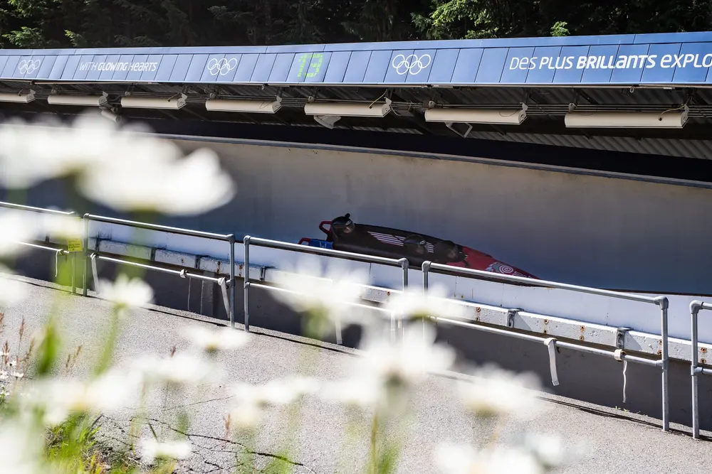 Bobsled track with single bobsled, foreground flowers.